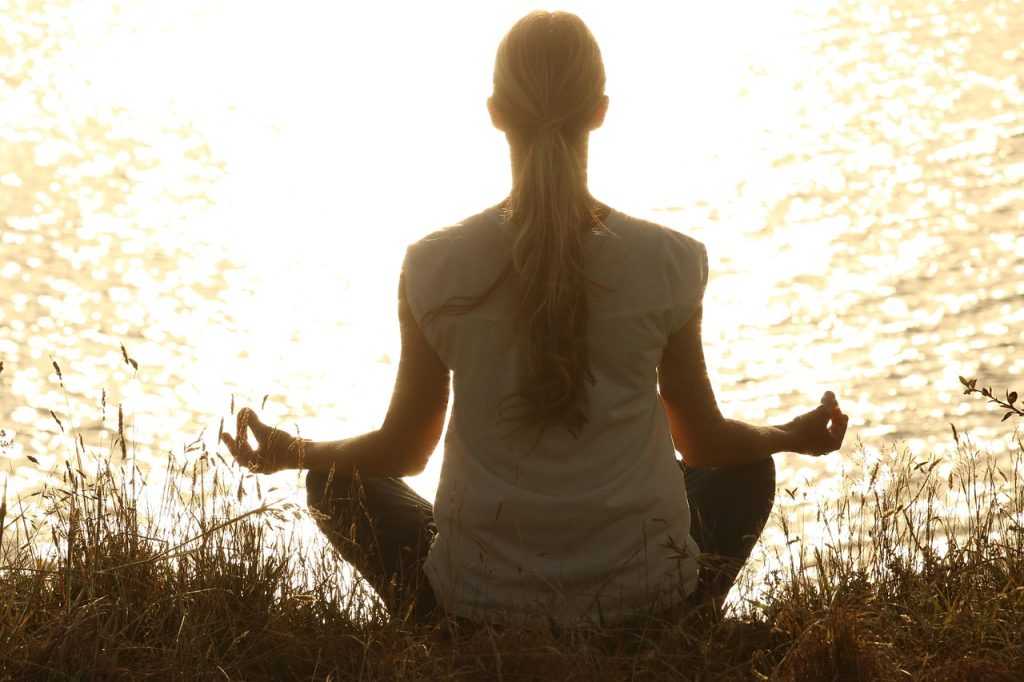 Woman meditating in front of water